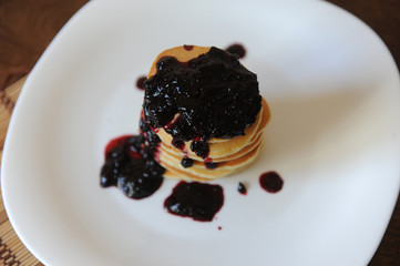 Homemade sweet pancakes with berry jam on a white plate