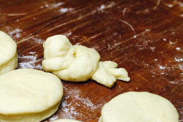 Small balls of fresh homemade dough and one in shape of bird for donuts on wooden board.