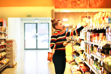 Woman shopping in supermarket reading product information