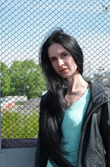 brunette girl with long hair on a background of metal mesh, youth, freedom,