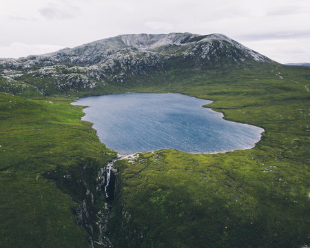 Lake surrounded by grassy landscape, mountains in background