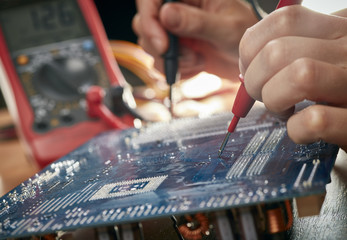 Technician checking motherboard with tester. Technological background. Shallow DOF