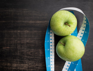 Green apple with measuring tape on wood background,top view