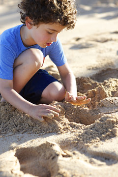 Young boy playing in sand at the beach