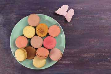 Macarons and paper butterfly on purple with copyspace