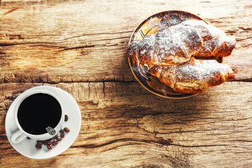 Coffee and croissant on wooden background