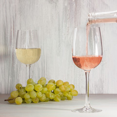 Rose wine poured into glass, with grapes in background