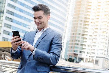 Fototapeta premium Westerner Business man talking via smart phone with skyscraper i