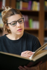 Female student in a library reading a book