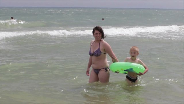 woman with a child standing in sea water
