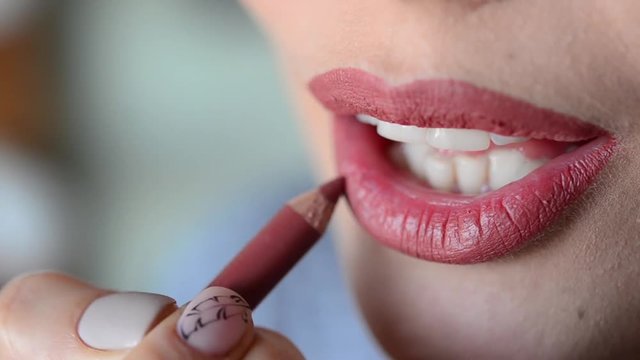 Woman doing lip contour with pink pencil