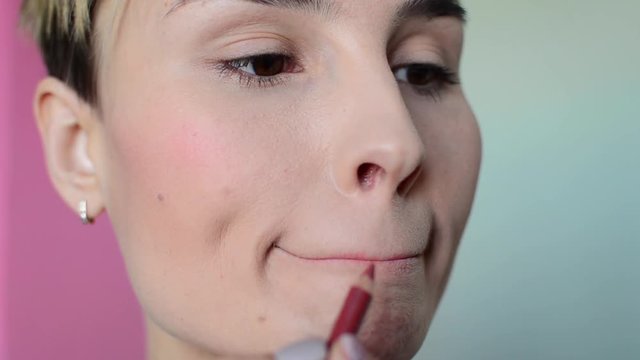 Woman doing lip contour with pink pencil
