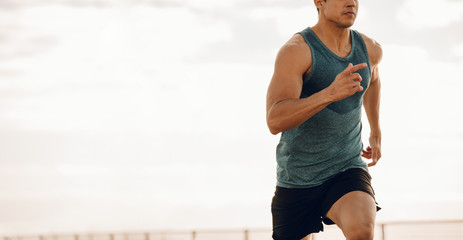 Young man running along a seaside promenade