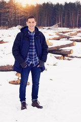 Handsome, stylish and smiling young man in jacket standing in the forest. Early spring, sunny day....