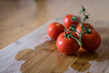 Fresh washed red cherry tomatoes on a wooden board. Close-up view. Red tomatos covered with water drops.