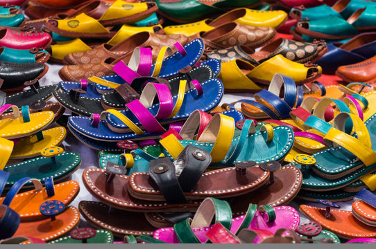 Pile of colorful handmade leather slippers spread out on a sidewalk for selling