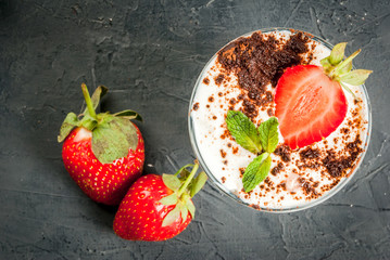     Summer dessert, classic cheesecake with strawberries decorated with mint leaves. n dark gray stone table. Copy space