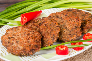 liver pancakes or cutlets with chili pepper and green onions on a wooden background