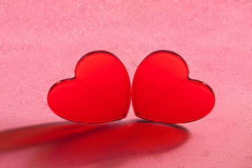 Fototapeta premium Two red hearts on a pink background with bokeh. Saint Valentine's Day. Greeting Card. Invitation to love.