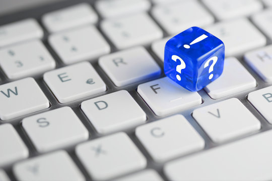 Blau farbener / blauer W&uuml;rfel auf Tastatur mit Fragezeichen und Ausrufezeichen - FAQ Frage Antwort