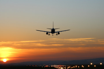 Plane lands at an airfield on the background of sunset