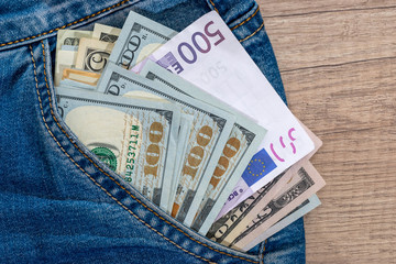 dollar and euro bills inside jeans pocket.