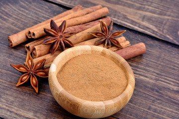 Group of cinnamon sticks and star anise with cinnamon powder in a bowl