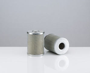 two automotive filter cylindrical shape  on a white background with reflection