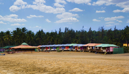 Colorful huts in Agonda beach with palm trees background in Goa, India