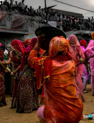 Very colorful Holi festival in India celebration - women beating men with bamboo sticks