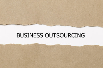 business outsourcing word written under torn paper.