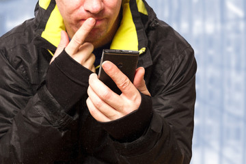 Mann in Ski Jacke überlegt am Telefon 