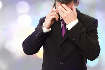 Gesch&auml;ftsmann h&auml;lt sich den Kopf beim telefonieren    
