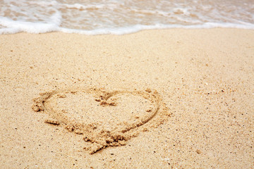 Heart symbol on the sand and sea wave.