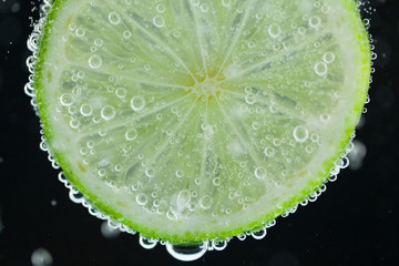Fototapeta na wymiar Lime slice falling into water