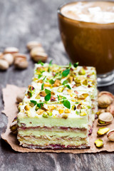 Slices  of layered cake with pistachio and a cup of coffee with