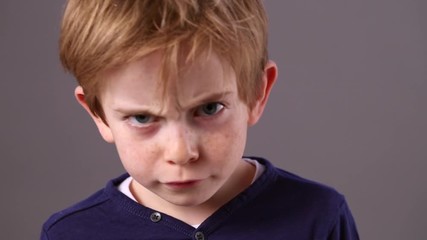 closeup of angry little boy with freckles with dirty look