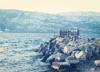Dock and rocks on lake in winter