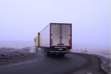 Fototapeta na wymiar Truck at the roundabout in the fog, frost, cold winter morning.