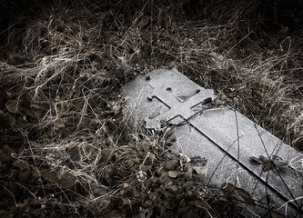 Brompton, London - Ancient grave marker / gravestone with medieval cross engraving laying in grass.