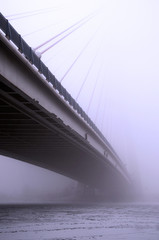 Suspension bridge in the fog, frost, cold winter morning.