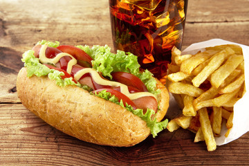 Hotdog with french fries on napkin with glass of cola