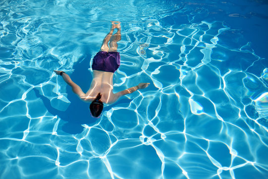 Top View Of A Man Swimming In A Swimming Pool On Sunny Summer Day