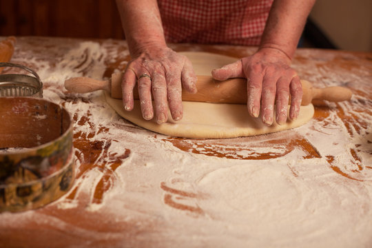Senior woman hands rolling out dough  flour with rolling pin,hom