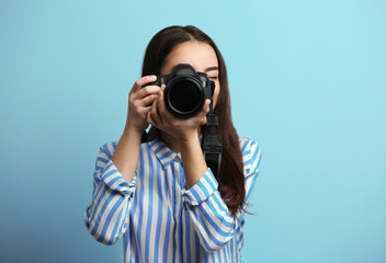 Beautiful young photographer on color background