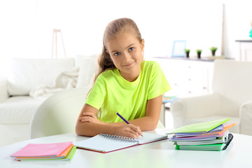 Attractive little girl sitting at table and doing home tasks