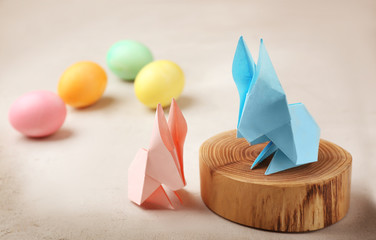 Origami paper bunnies and Easter eggs on light background