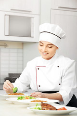 Young woman chef with different dishes on plates in modern kitchen
