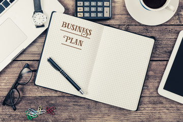 Business Plan text on note pad, Office desk with computer techno