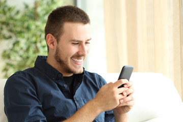 Happy guy using a mobile phone at home